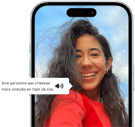 Un iPhone 15 affichant une annonce VoiceOver décrivant le contenu d’une photographie en ces termes : une personne aux cheveux noirs ondulés en train de rire