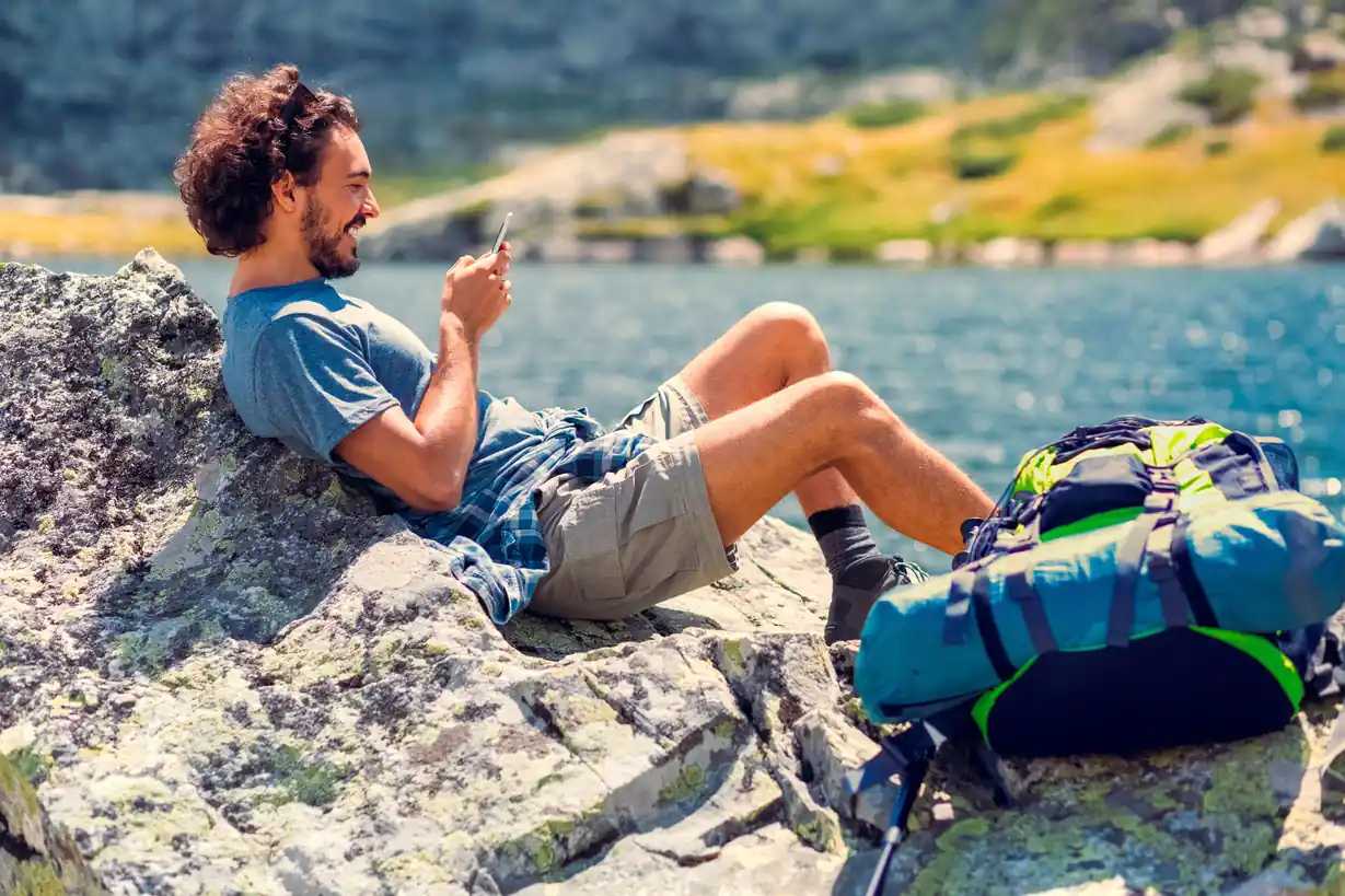 Un randonneur allongé sur une montagne qui regarde son téléphone portable