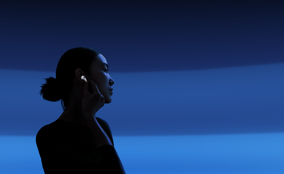 Une personne tenant la tige de ses AirPods 5 entre le pouce et l’index pour changer les modes d’écoute