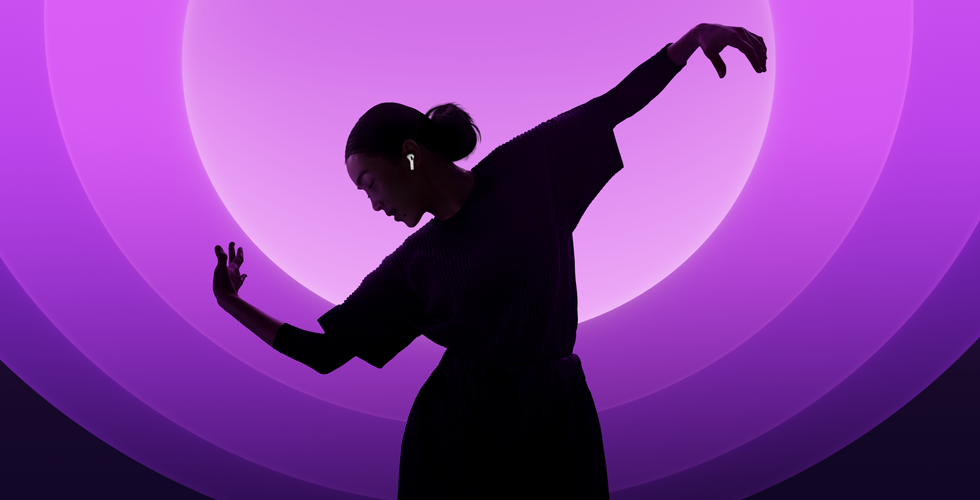 Une personne danse avec ses AirPods 5 aux oreilles, sur fond multicolore