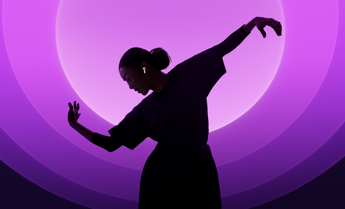 Une personne danse avec ses AirPods 5 aux oreilles, sur fond multicolore