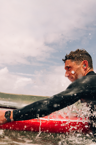 Un homme sur une planche de paddle, dans l’eau, porte une Apple Watch Series 10.