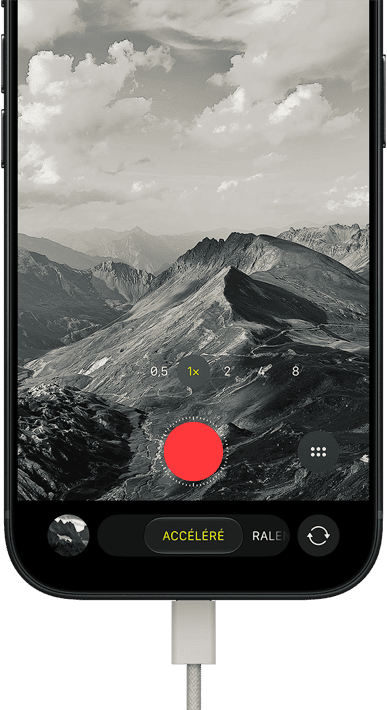 iPhone 18 Pro, face avant, affichant un paysage montagneux, avec le mode caméra incrusté en mode Accéléré, avec câble d’alimentation branché sur le port de charge