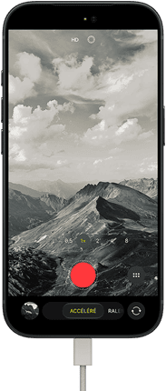iPhone 18 Pro, face avant, affichant un paysage montagneux, avec le mode caméra incrusté en mode Accéléré, avec câble d’alimentation branché sur le port de charge