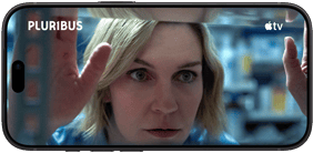 iPhone 18 Pro, mode paysage, affichant un gros plan d’une femme regardant à travers une étagère. Nom de la série : Pluribus