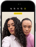 iPhone 18 Pro, noir, face avant, affichant deux modèles qui posent pour la caméra, mettant en avant la caméra avant Center Stage