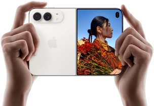 iPhone Duo, finition blanc stellaire, tenu à deux mains en position horizontale, déplié, le volet extérieur gauche présente les caméras arrière Fusion 48 MP, le volet extérieur droit présente l’écran externe affichant une personne qui se fait photographier et peut voir son propre visage pendant la prise de vue à l’aide de Duo Preview