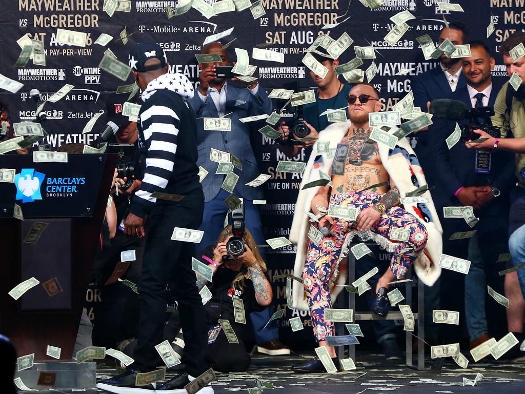 Floyd Mayweather (à gauche et de dos) a fait pleuvoir les billets sur Conor McGregor (assis à droite)